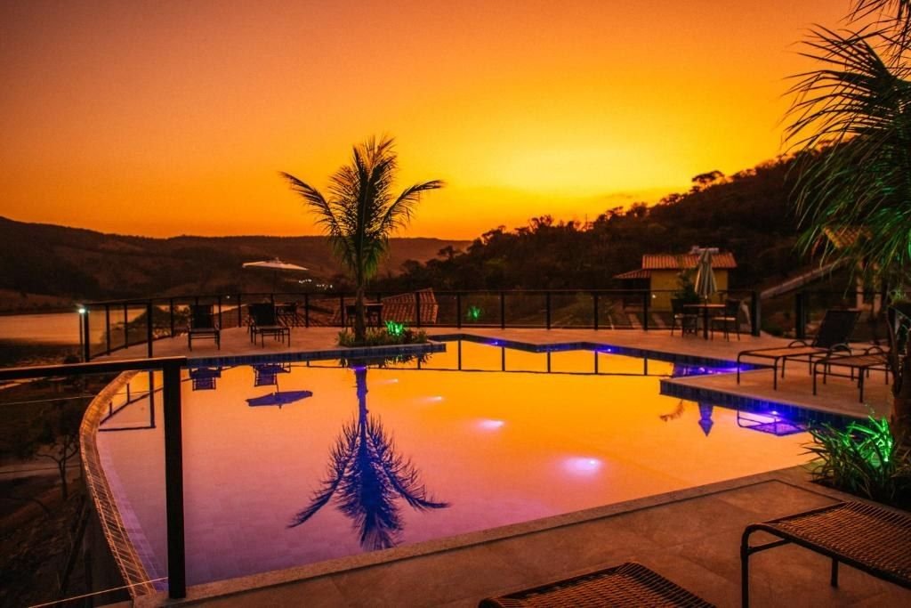 Piscina ao pôr do sol com o coqueiro refletido na água